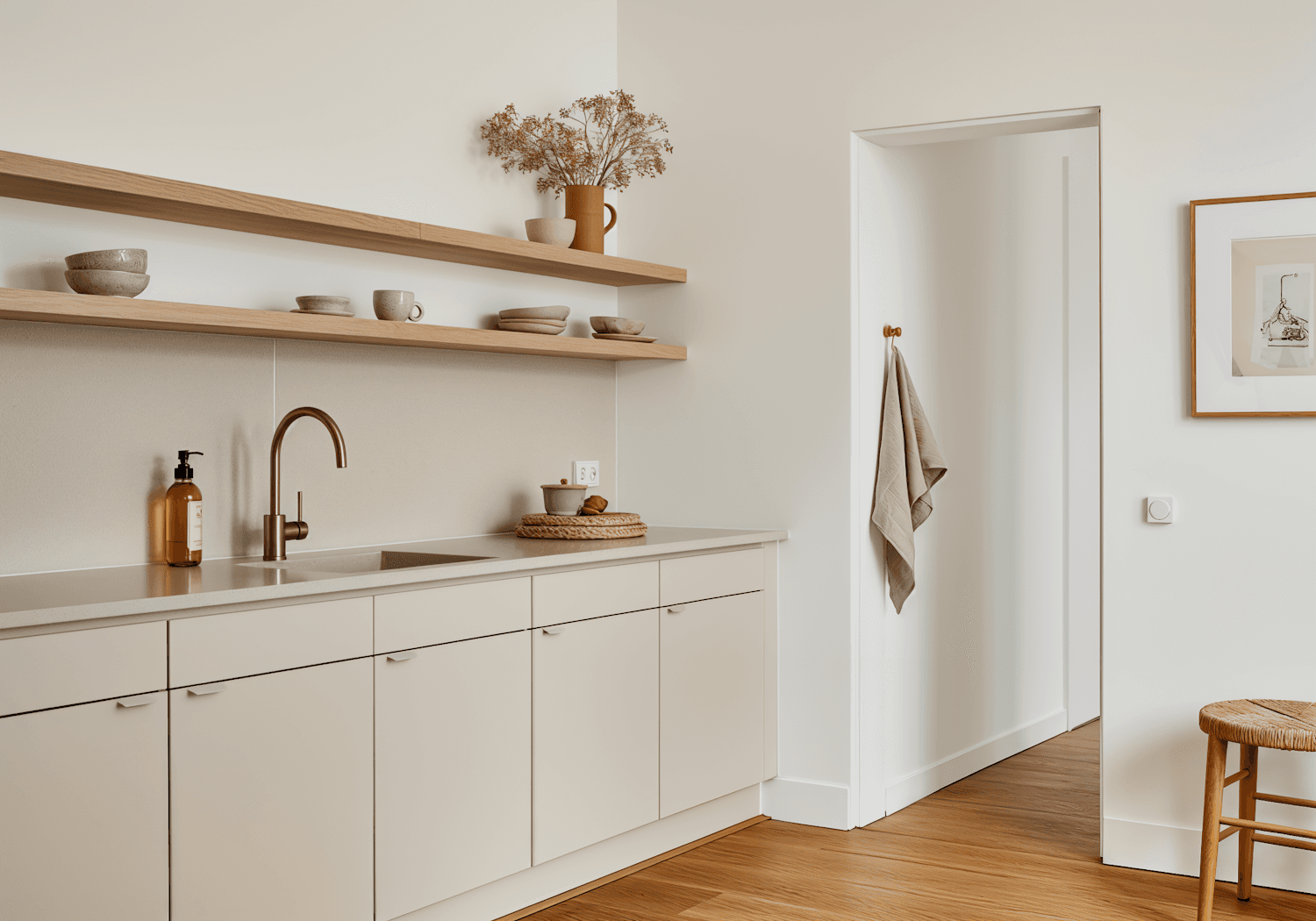 Minimal kitchen with warm beige cabinets, open wooden shelving and a brass tap